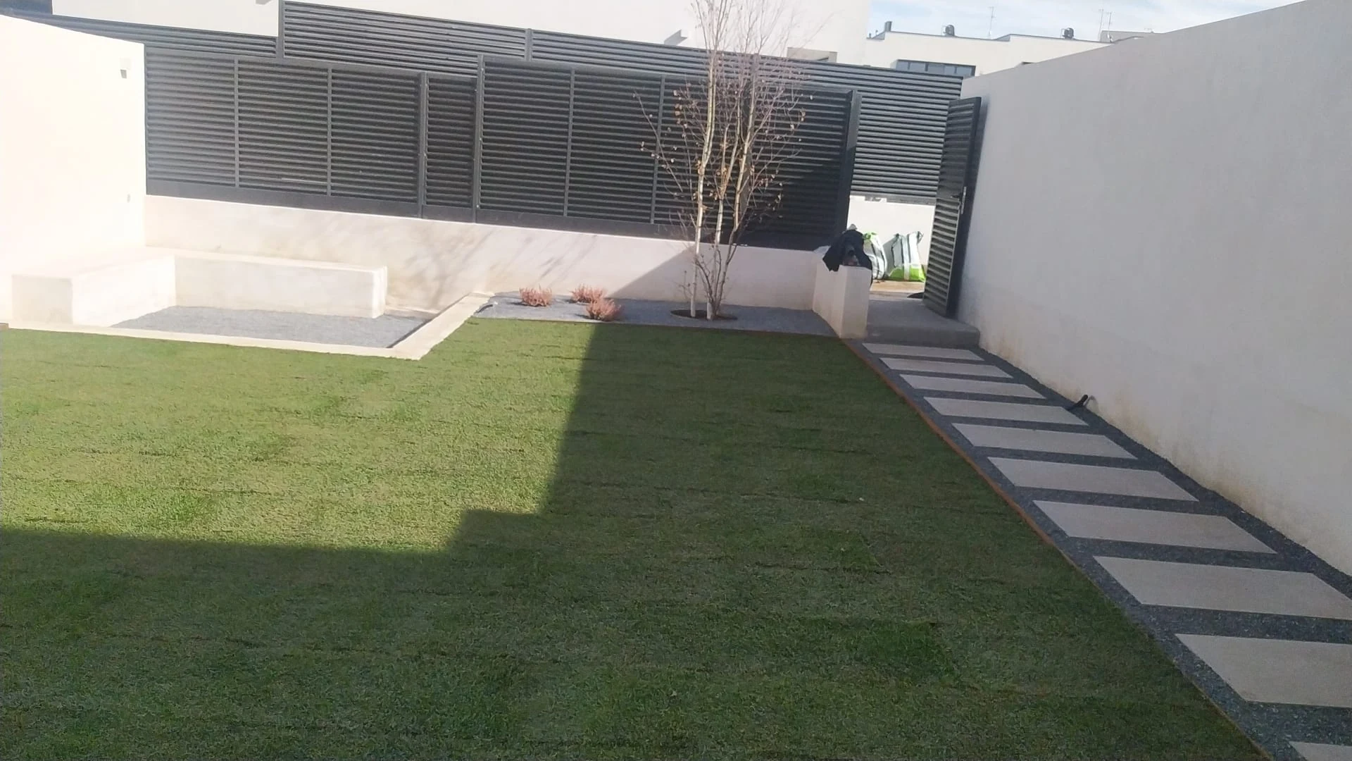 Jardín terminado con césped, camino de losas, grava y plantación ornamental