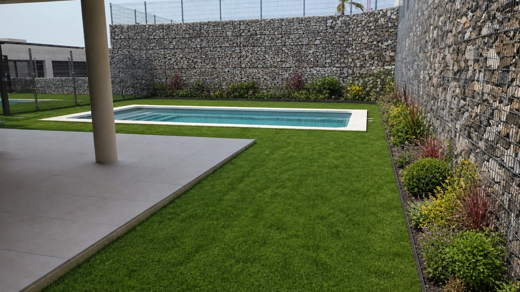 Entorno de piscina terminado con césped y plantación perimetral
