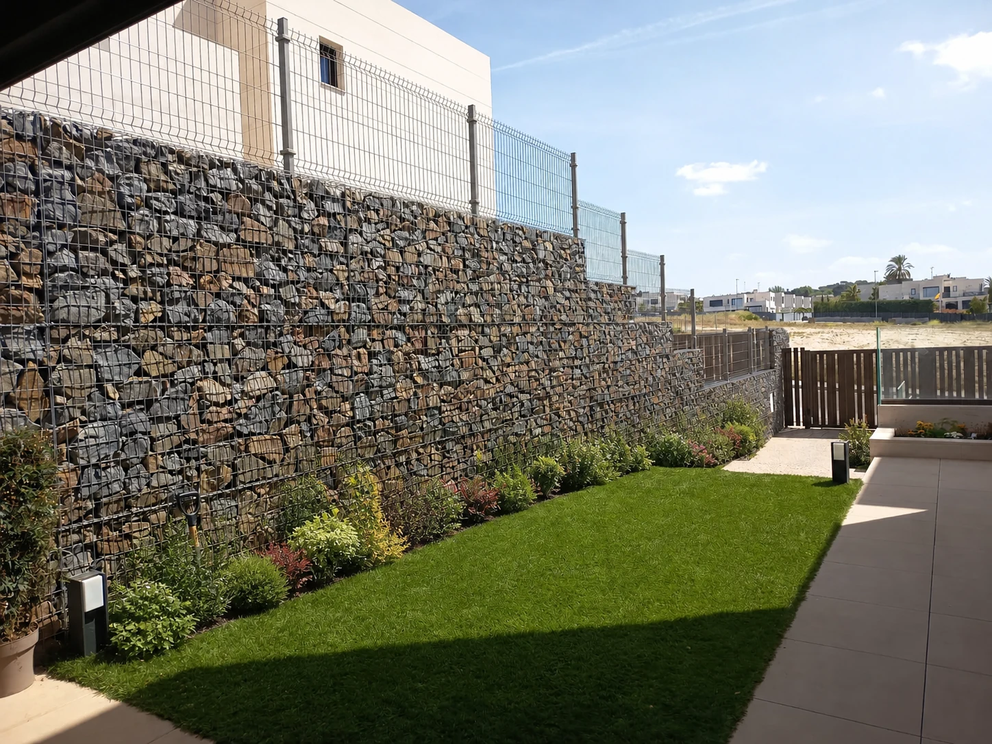 Pradera de césped junto al muro de gaviones y parterre lineal evolucionado