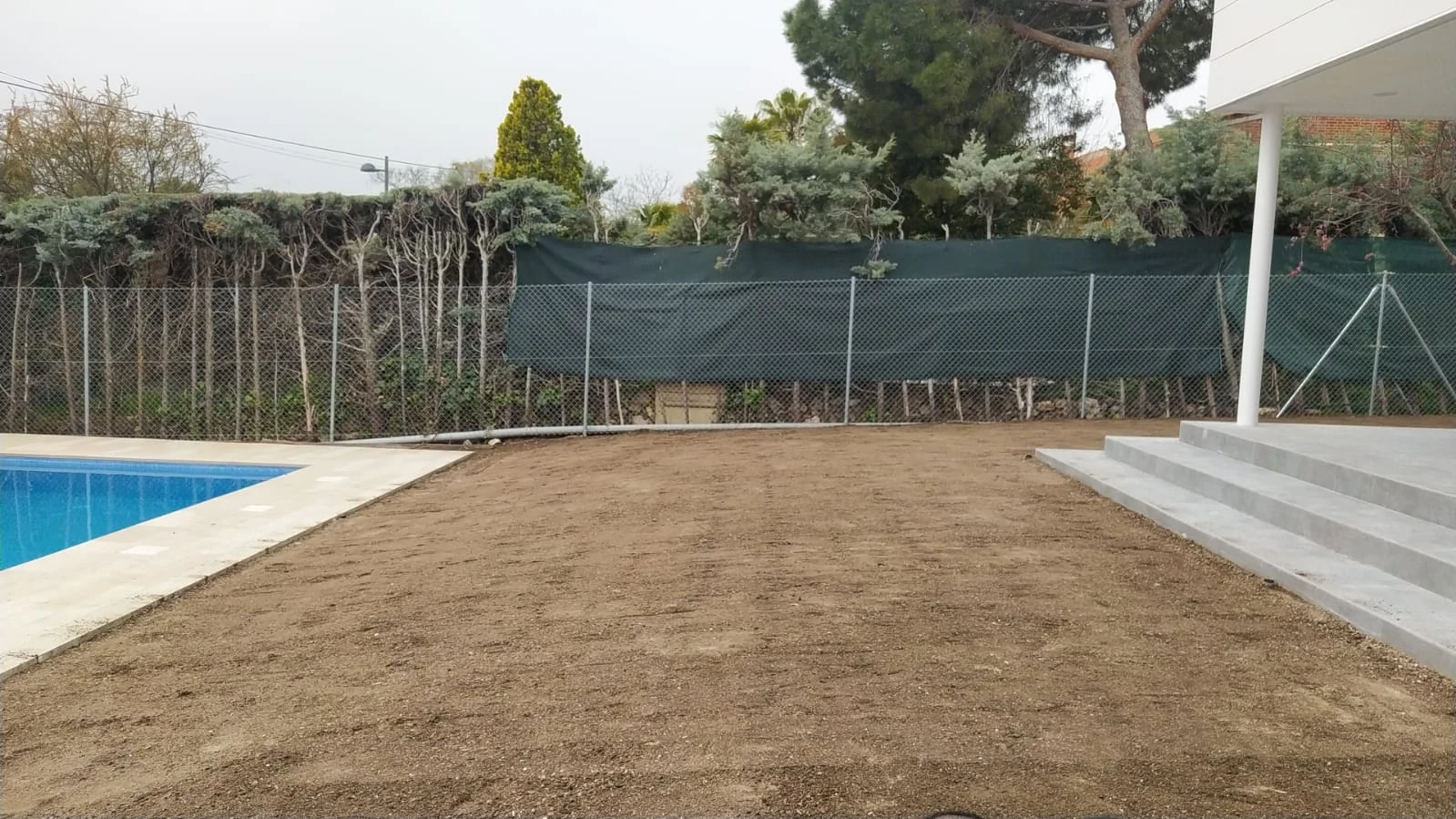 Terreno preparado junto a la piscina antes de instalar el césped